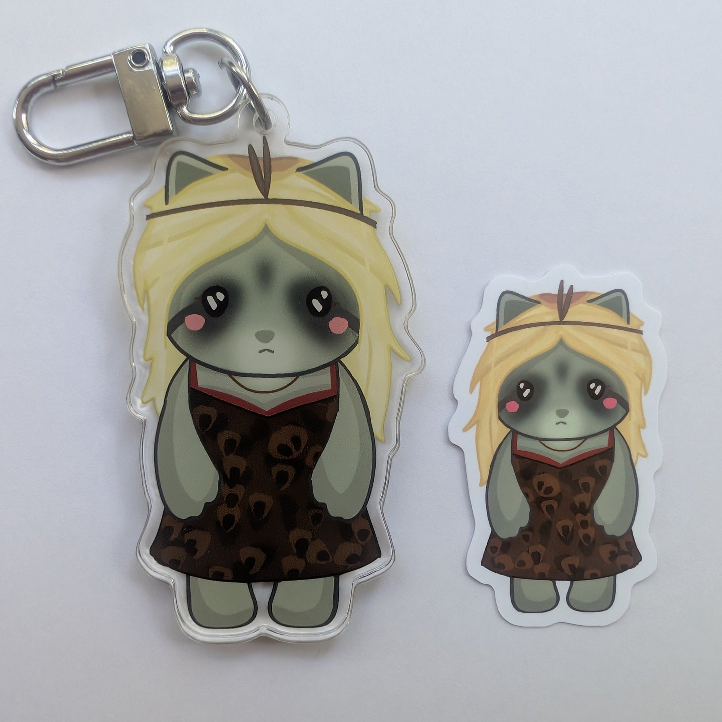 Two cartoon natalie animal keychains with blonde hair and dark eyes, one large and one small, both wearing a leopard-print dress, shown on a plain light background.